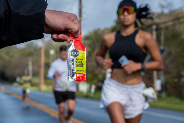 GU Roctane Cherry Lime Energy Gel with runner in a race