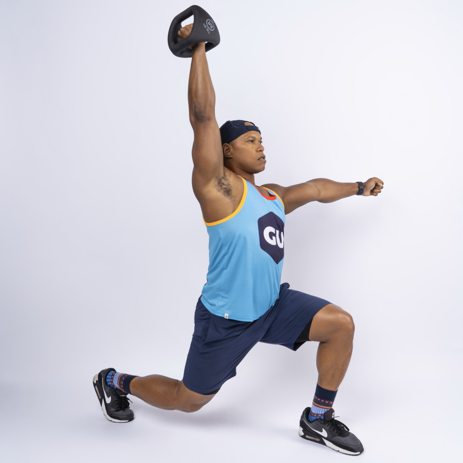 man in a GU tank top lifting a kettlebell